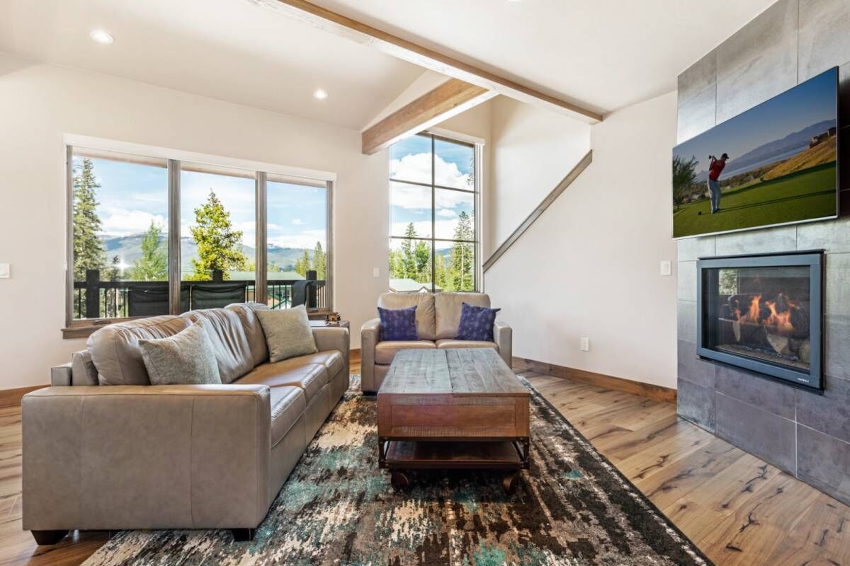 Un salón espacioso con chimenea, ventanas amplias y vistas al exterior.