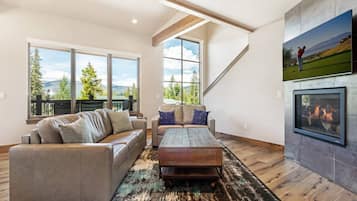 Un salón espacioso con chimenea, ventanas amplias y vistas al exterior.