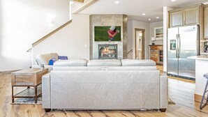 Ein Wohnzimmer mit einer großen Couch, einem Kamin und einer Küchenzeile mit einem Kühlschrank.