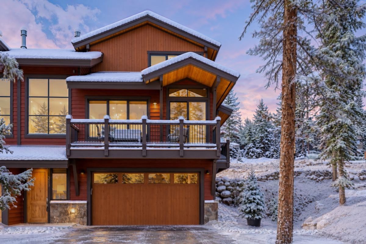 Une maison en bois à deux étages, dotée d’un balcon, de grandes fenêtres et d’un garage.