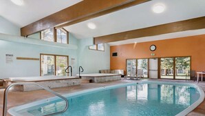 En swimmingpool med en solterrass, en klocka på väggen och en sittgrupp med utsikt över omgivningarna.