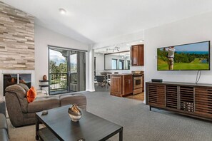 A modern living room with a sofa, coffee table, and a television mounted on the wall. - Lakeview | Walkable • Hot Tub • Close to Resorts! (Dillon)