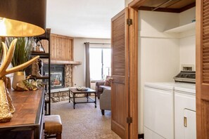 A living room with a fireplace, a sofa, a coffee table, and a wooden cabinet. - Nature Retreat • Near Trails & Resorts • Hot Tub! (Silverthorne)