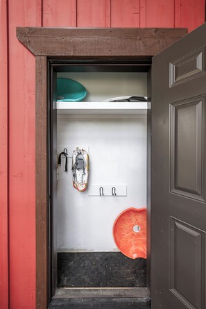 A compact storage area with a red door, a white wall, and a black textured mat at the entrance. - Alpine Ambiance | Luxury 4BR • 3 Decks • Hot Tub (Keystone)
