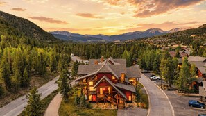 A lodge with a prominent red facade, surrounded by a forested area with a mountain backdrop. - Alpine Ambiance | Luxury 4BR • 3 Decks • Hot Tub (Keystone)