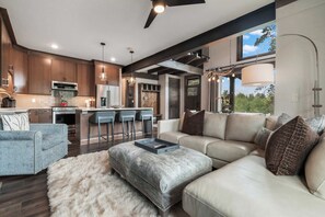 A modern kitchen with dark wood cabinets, stainless steel appliances, and a bar area with stools. - Alpine Ambiance | Luxury 4BR • 3 Decks • Hot Tub (Keystone)