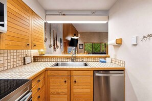 Eine moderne Küche mit Holzschränken, einer Edelstahl-Spüle und einem Geschirrspüler.