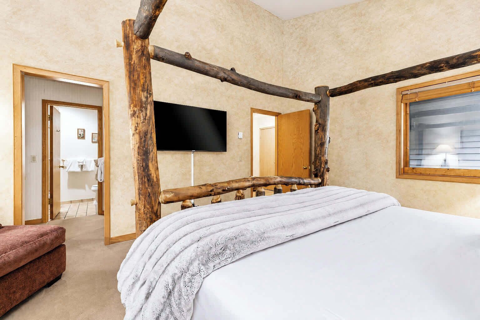 A room with a bed, a television, and a wooden structure resembling a tent.