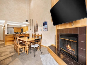 Un salon moderne avec une cheminée, des meubles en bois et un téléviseur à écran plat fixé au mur.
