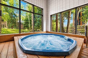 A hot tub in a room with large windows overlooking a garden. - Mountainside | Garage | Hot Tub | Steps to Lifts! (Keystone)