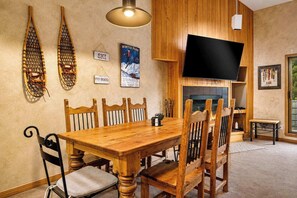 A wooden dining table with chairs, a television mounted on the wall, and a fireplace. - Mountainside | Garage | Hot Tub | Steps to Lifts! (Keystone)