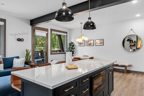 Una cocina moderna con una isla grande, armarios negros e iluminación colgante.