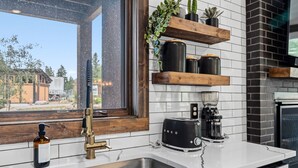 Una cucina moderna con lavello in acciaio inossidabile, una macchina da caffè nera e un tostapane.