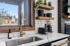 A modern kitchen with a stainless steel sink, a black coffee maker, and a toaster. - All Seasons Retreat | Private Hot Tub | Steam Room (Keystone)