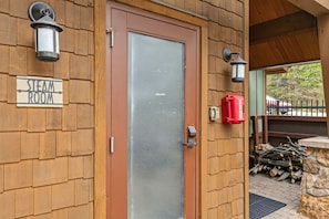 A wooden building with a sign reading 'STEAM ROOM' and a door with a glass panel. - All Seasons Retreat | Private Hot Tub | Steam Room (Keystone)