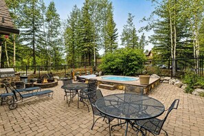 An outdoor patio with a hot tub, seating, and a grill area surrounded by trees. - All Seasons Retreat | Private Hot Tub | Steam Room (Keystone)