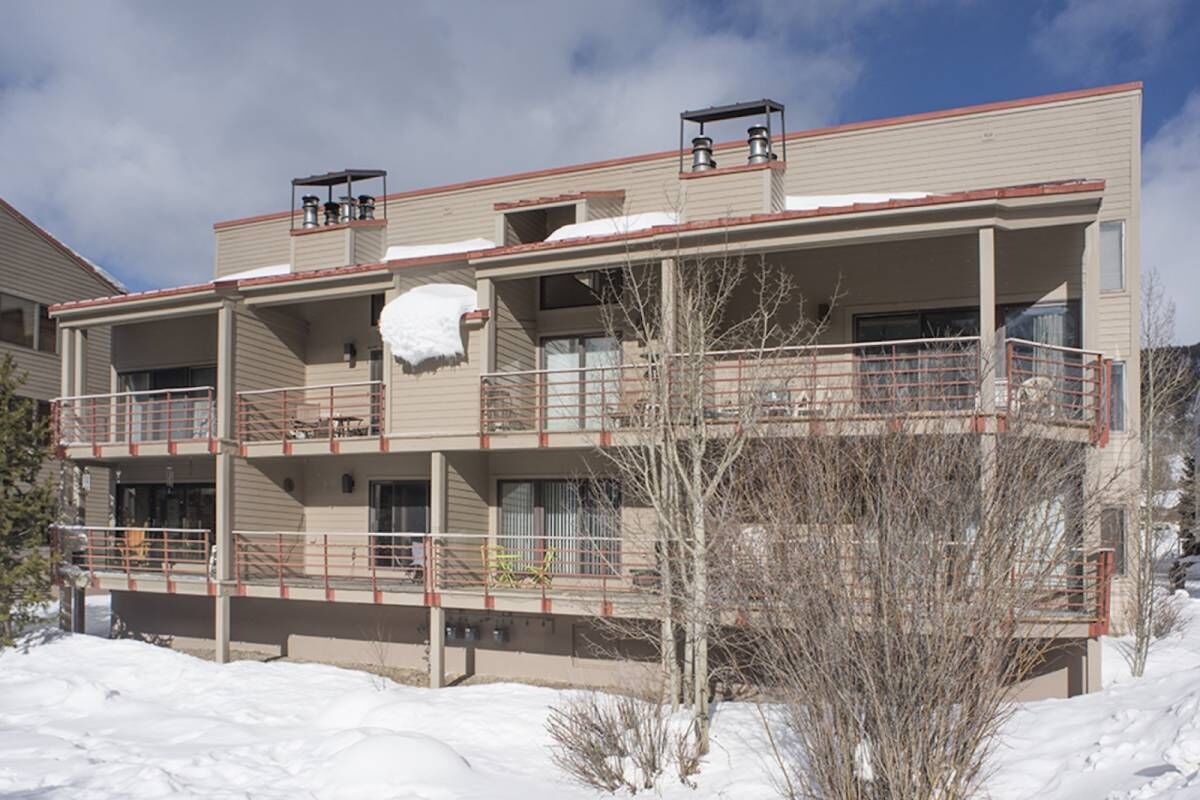 A multi-story building with balconies, a covered outdoor area, and snow on the roof.
