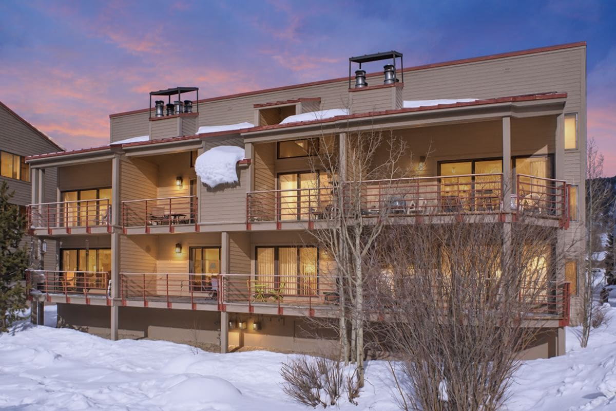 A multi-story building with balconies, large windows, and a snow-covered roof.