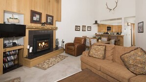 A living room with a fireplace, leather armchair, and a sofa with patterned cushions. - Slopeside | Hot Tub • Garage • Pool • Ski Locker! (Keystone)