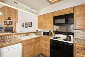 A kitchen with wooden cabinets, a microwave, a stove, and a dishwasher. - Slopeside | Hot Tub • Garage • Pool • Ski Locker! (Keystone)
