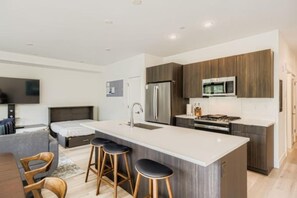 A modern kitchen with a central island, stainless steel appliances, and wooden cabinetry. - New Riverfront Home | Near Six Resorts • Hot Tub! (Silverthorne)