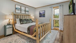 Une chambre à coucher avec un lit en bois, une table de chevet, un téléviseur et une fenêtre avec des rideaux.