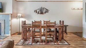 Un espace repas comprenant une table et des chaises en bois, un tapis à motifs et une œuvre d’art accrochée au mur.