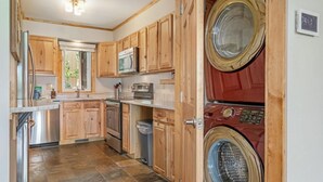 Une cuisine compacte avec des meubles en bois, un four à micro-ondes, une cuisinière et un lave-linge.