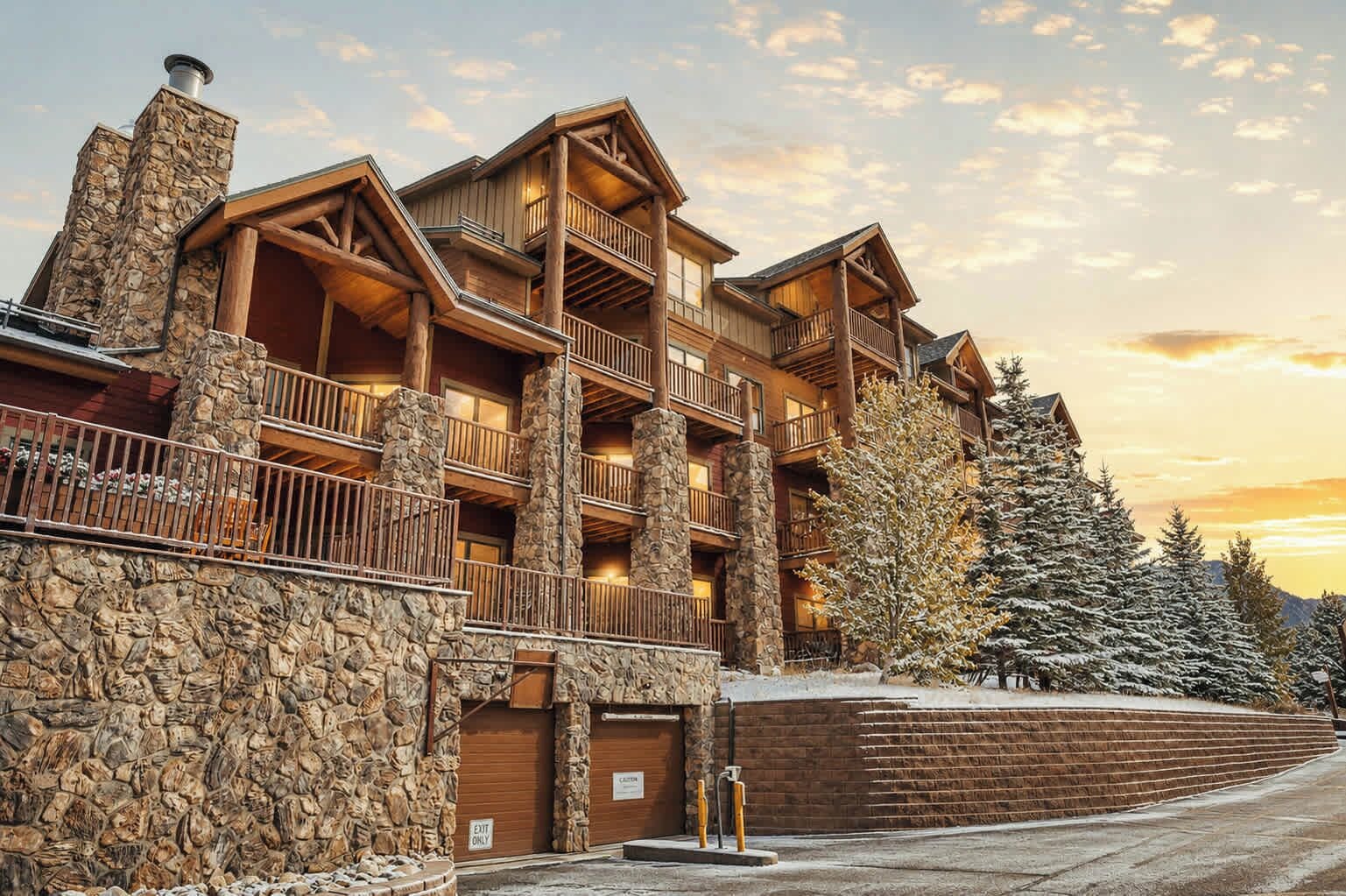 A multi-story lodge with stone pillars, balconies, and a snow-covered landscape.
