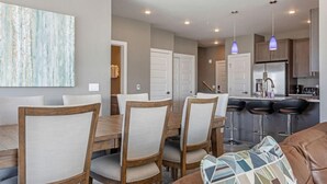 A dining area with a wooden table and chairs, a kitchen with stainless steel appliances, and a bar area with stools. - Penthouse Retreat • Stunning Views • Near Resorts! (Dillon)