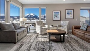 A modern living room with a sofa, armchairs, a coffee table, and large windows with a mountain view. - Penthouse Retreat • Stunning Views • Near Resorts! (Dillon)