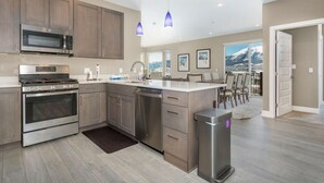 A modern kitchen with stainless steel appliances, wooden cabinets, and a view to the outside. - Penthouse Retreat • Stunning Views • Near Resorts! (Dillon)