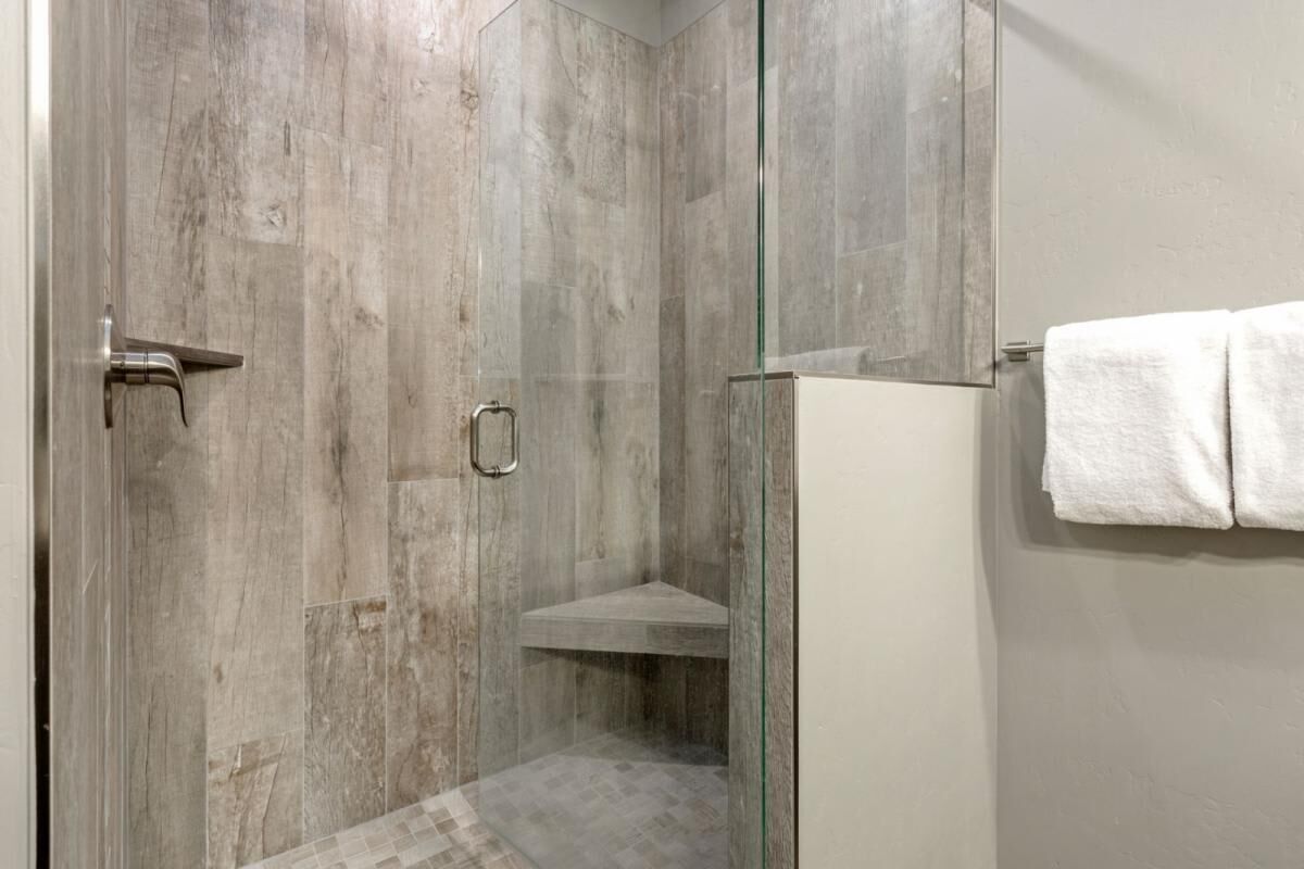 Ducha con puertas de vidrio, barra para toallas y asiento en la ducha.