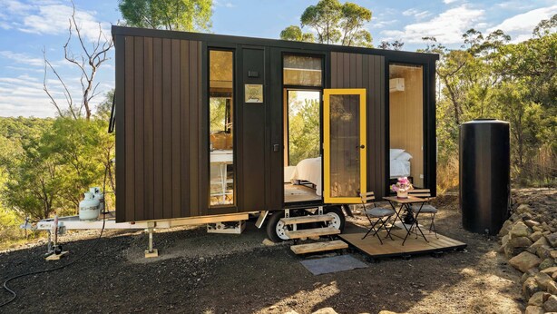 Een compacte, moderne cabin met een slaapgedeelte, een klein eethoekje en een zichtbare watertank.