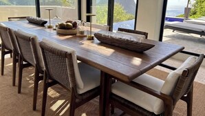 Una mesa de comedor con sillas, un tazón de fruta y un vaso de agua.