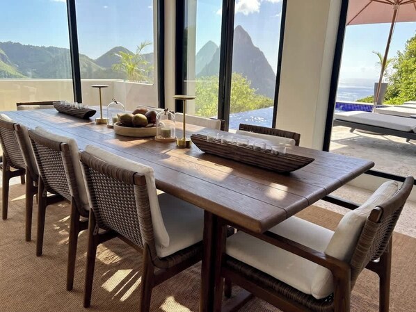 A dining table with chairs, a bowl of fruit, and a glass of water.