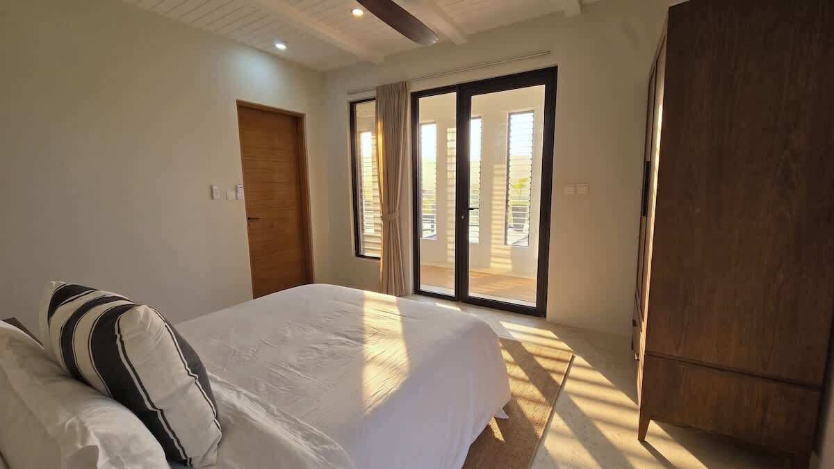 A bedroom with a bed, a wardrobe, and a sliding glass door leading to a balcony.