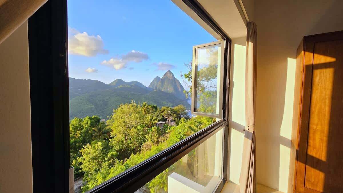 A room with a large window offering a view of mountains and greenery.