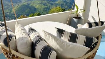 A hanging chair with cushions, a potted plant, and a view of mountains.