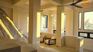 Un interior moderno con una escalera, ventanas amplias y una zona de estar.