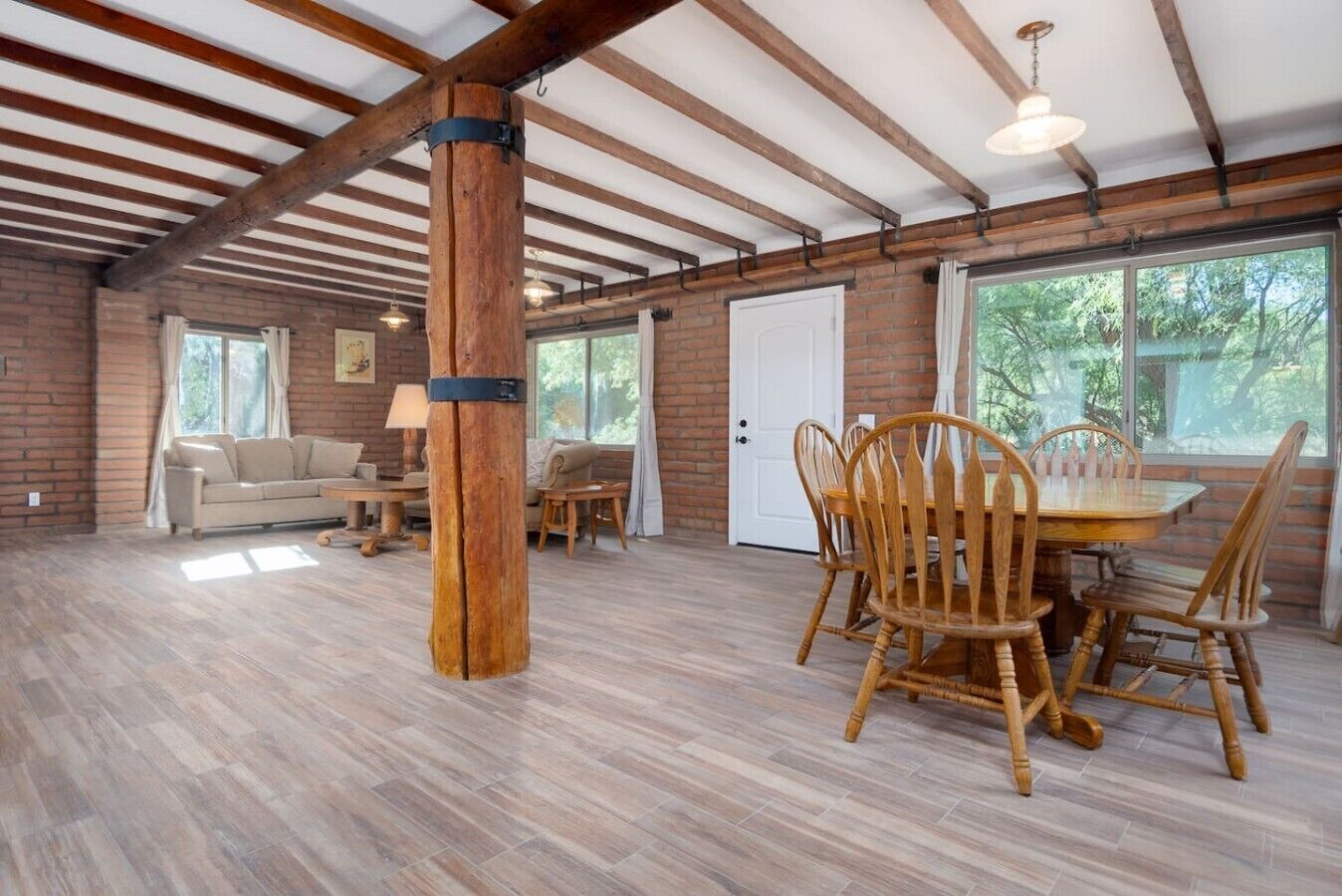 Une pièce spacieuse avec une table à manger en bois, des chaises, un canapé et une fenêtre.