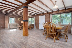 A spacious room with a wooden dining table, chairs, a sofa, and a window. - 1945 Ranch House / Tanque Verde / 2 BR 1 BA (Tucson)