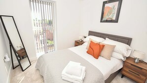 A bedroom with a bed, nightstands, a mirror, and a window with blinds. - Modern & Cosy 1 Bedroom Apartment in Leeds (Leeds)