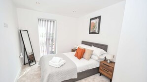A bedroom with a bed, nightstand, and a mirror. - Modern & Cosy 1 Bedroom Apartment in Leeds (Leeds)