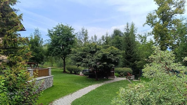 Un sendero en un jardín que lleva a un mirador rodeado de abundante vegetación y árboles.