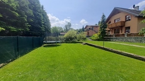 Ein gepflegter Rasen, ein Trampolin und ein Haus mit Balkon.