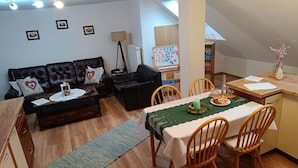 Una sala acogedora con un sofá, una mesa de comedor con sillas, una pizarra y una lámpara.