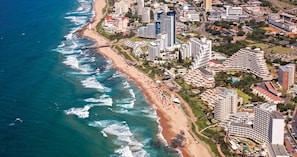 An aerial view of a coastal city with high-rise buildings, a beach, and a lighthouse. - Luxury 3 Bedroom Penthouse - Umhlanga Rocks (uMhlanga)