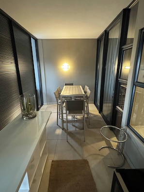 A dining area with a table and chairs, a potted plant, and a wall-mounted light fixture. - Luxury 3 Bedroom Penthouse - Umhlanga Rocks (uMhlanga)