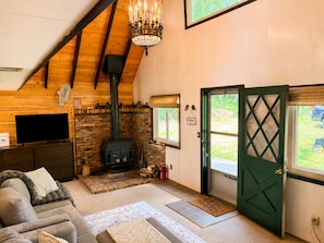 Una habitación acogedora con chimenea, televisor, sofá y puerta que da al exterior.
